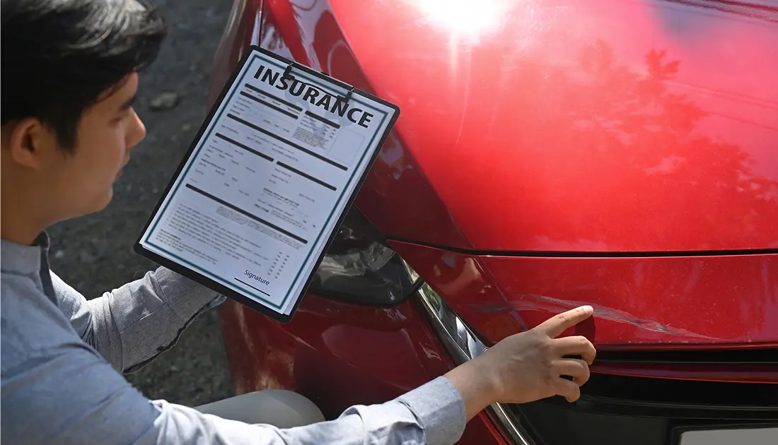 Individual holding insurance paper near vehicle