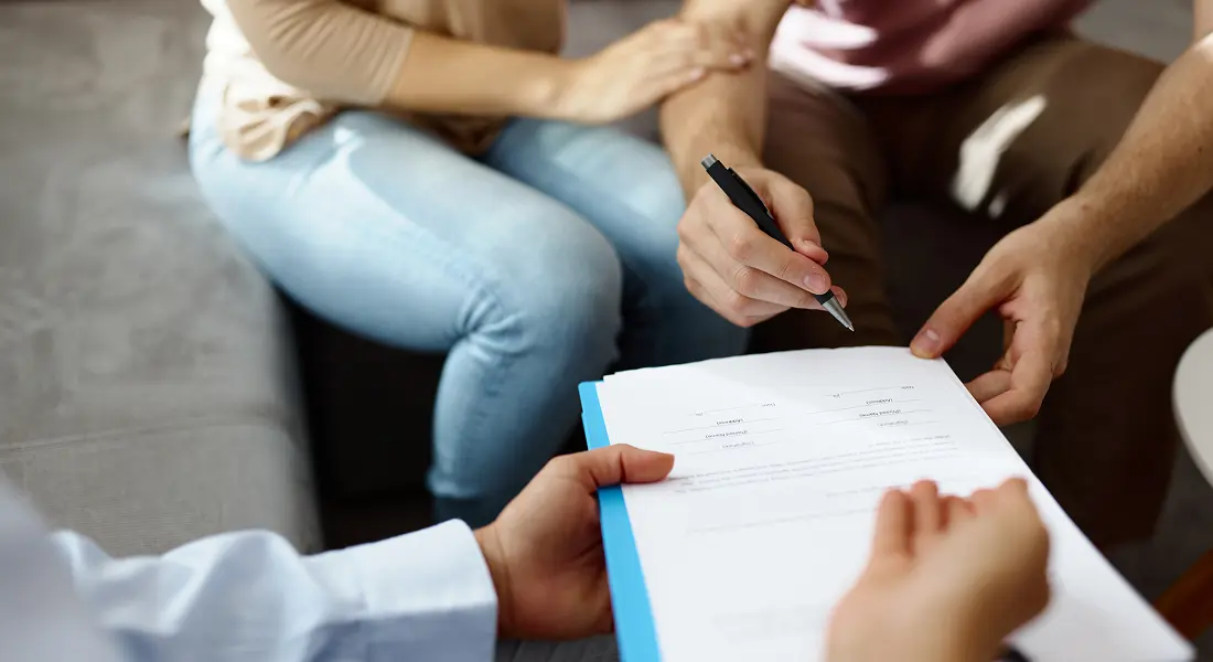 Hands passing a document for signature
