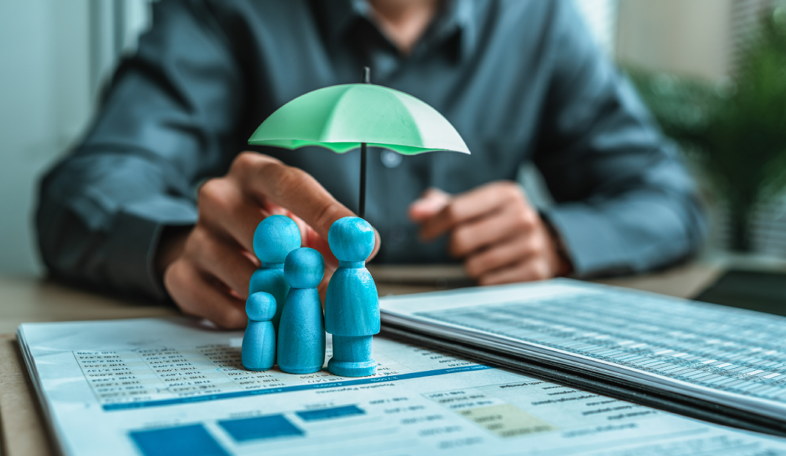 A hand holding a green umbrella over blue figurines representing a family.