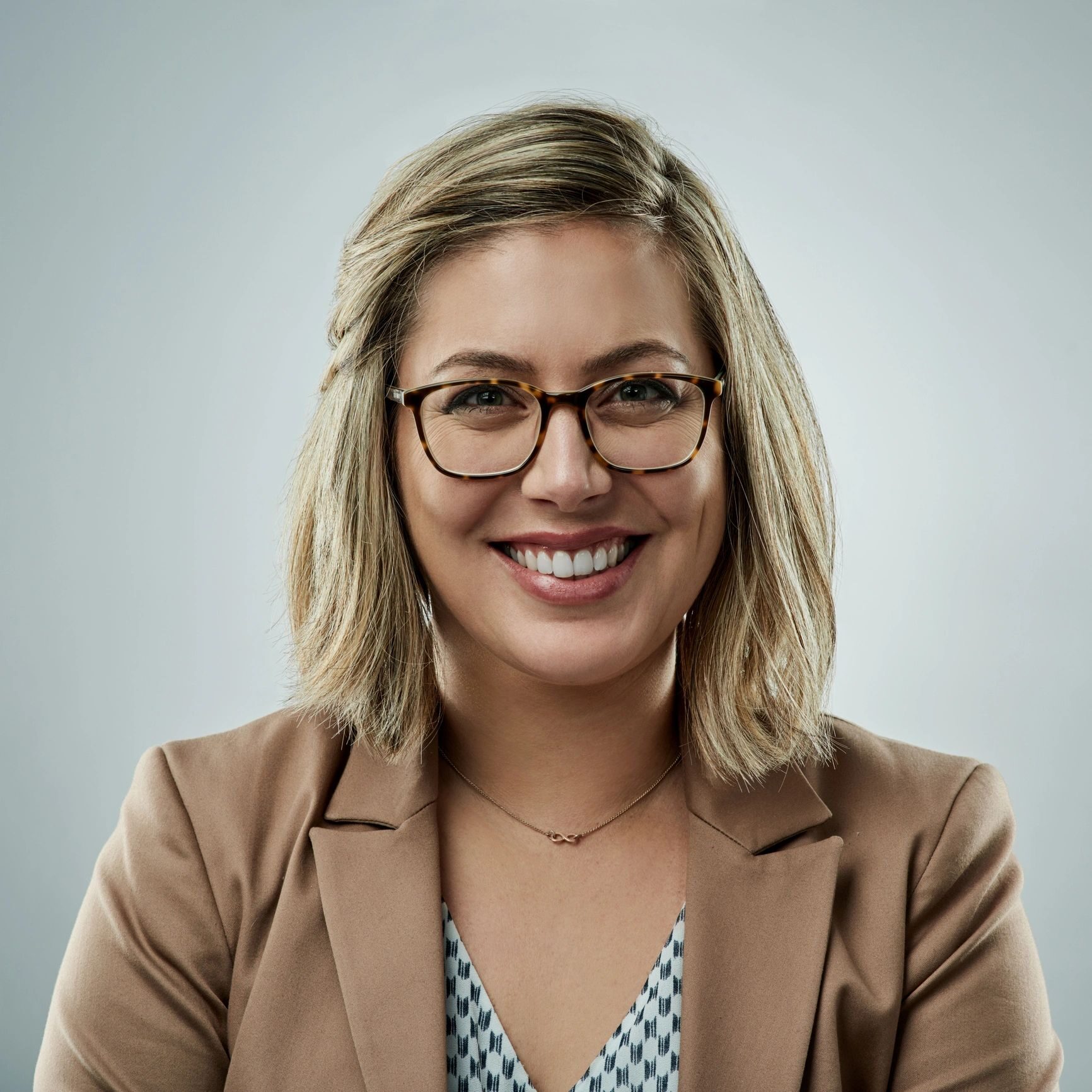 Smiling person with glasses and blazer